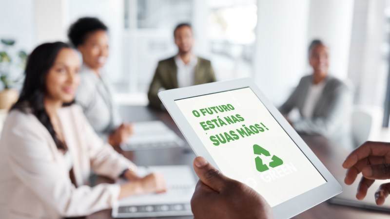 Blog Ambiental • Tela de tablet com mensagem motivacional sobre sustentabilidade durante reunião corporativa.