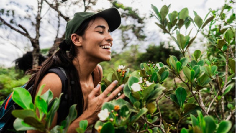 Mulher sorridente aprecia de perto a vegetação e flores da Mata Atlântica