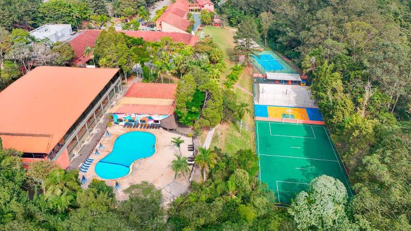 Blog Ambiental • Vista aérea do Hotel Terras Altas, mostrando piscina, quadras esportivas e áreas arborizadas, integradas à vegetação nativa da região.