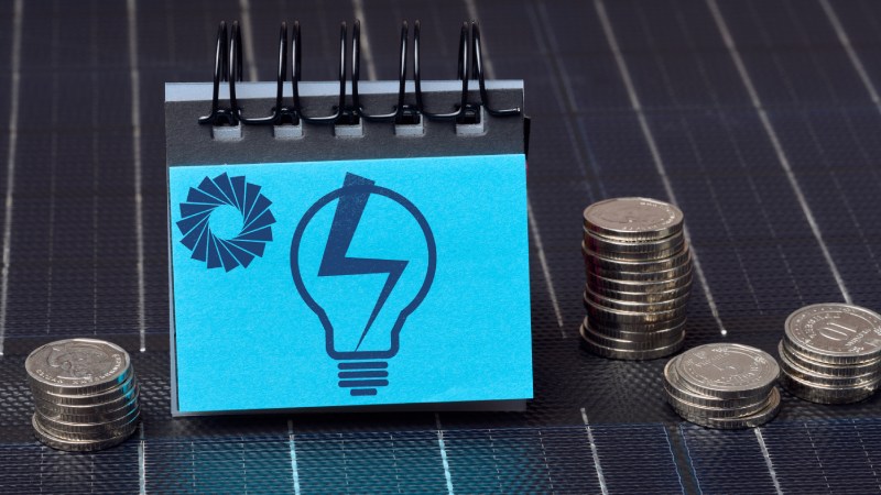 Blog Ambiental • Custos financeiros da energia renovável representados por moedas e painel solar.