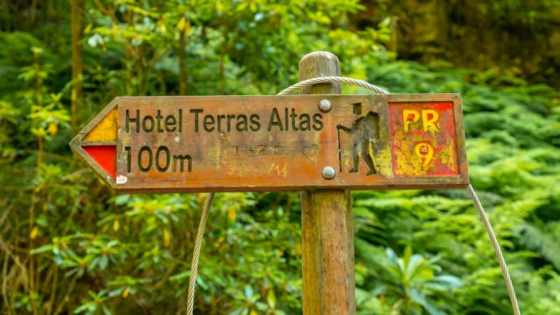 Placa indicativa em trilha natural apontando para hotel em área preservada