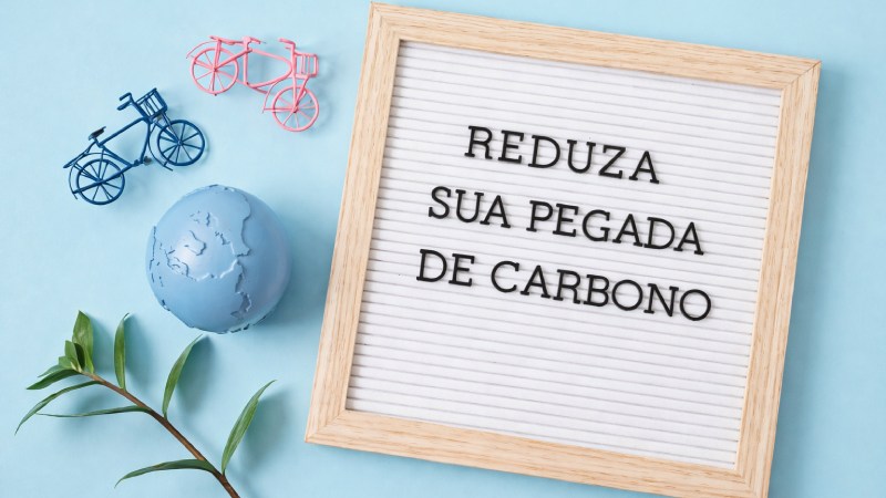 Blog Ambiental • Reduza sua pegada de carbono mensagem em placa com elementos sustentáveis como bicicleta, planta e planeta Terra