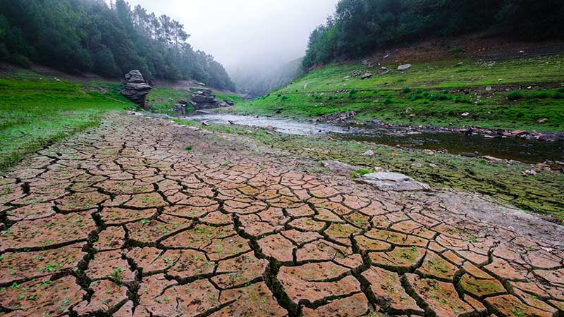 Blog Ambiental • Solo rachado em um leito de rio seco, ilustrando os efeitos da crise hídrica e o mito de que a água é um recurso inesgotável.